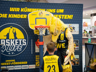 EWE Baskets Maskottchen mit einem Fan