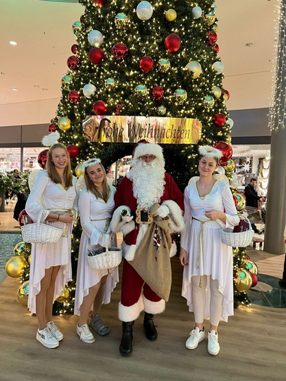 Engel und Weihnachtsmann vor dem Weihnachtsbaum